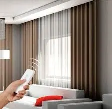 Hand holding a remote for motorized brown drapes and white sheers