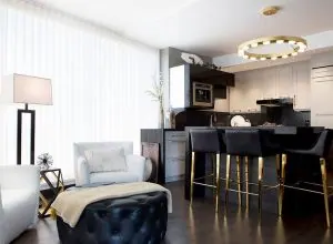 Rideaux blancs longs dans un salon ouvert sur cuisine et îlot à tabourets